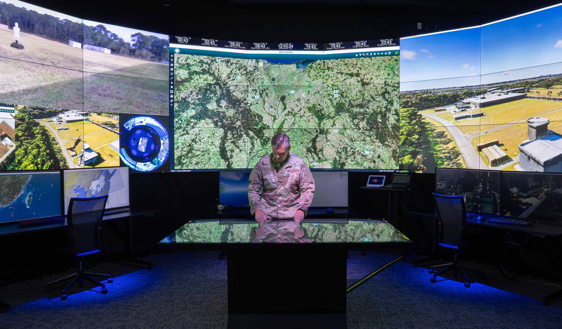 Solider standing inside simulation center with screens all around