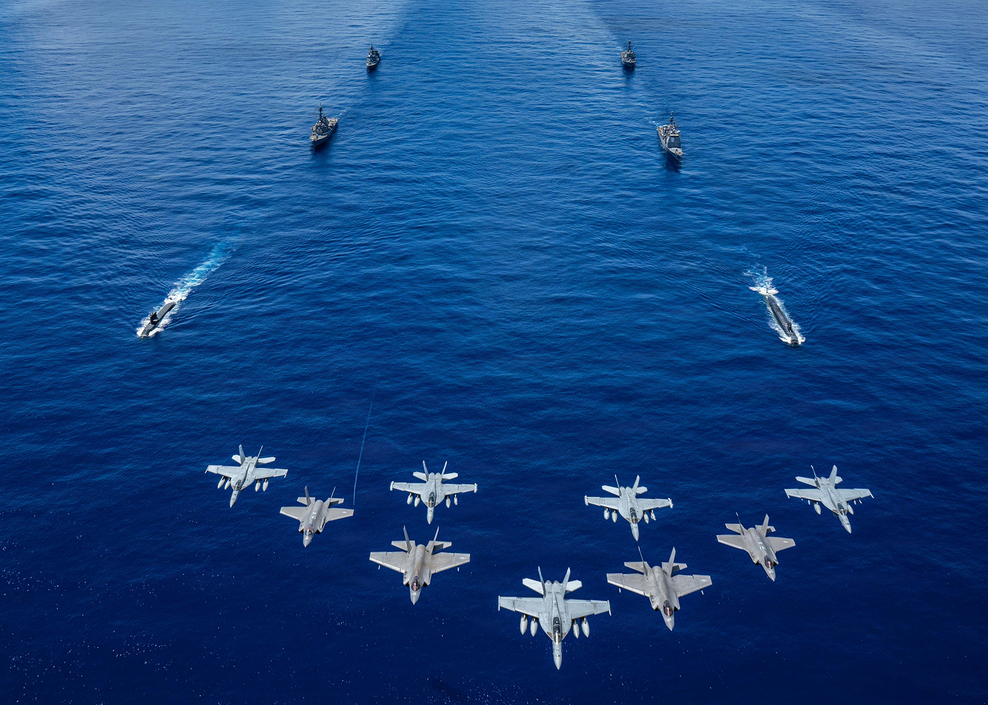 Jets flying in formation over water with Navy ships