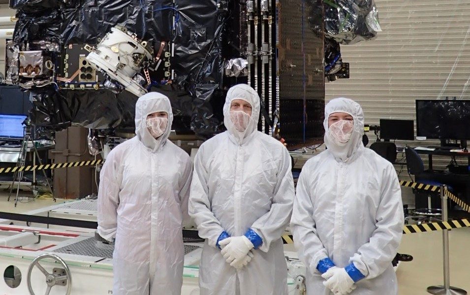 Jamie stands in front of the GOES-S satellite flanked by two Colorado State fellowship award recipients.
